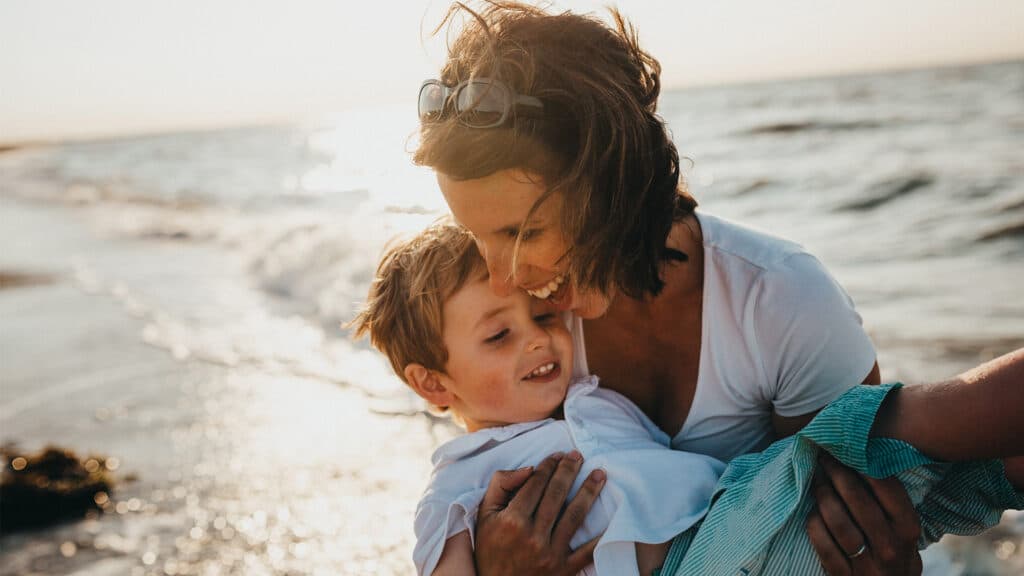 mom holding son at beach