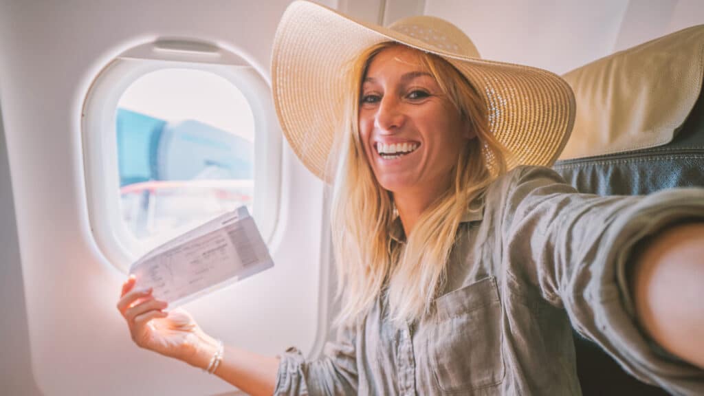 woman smiling on airplane with ticket