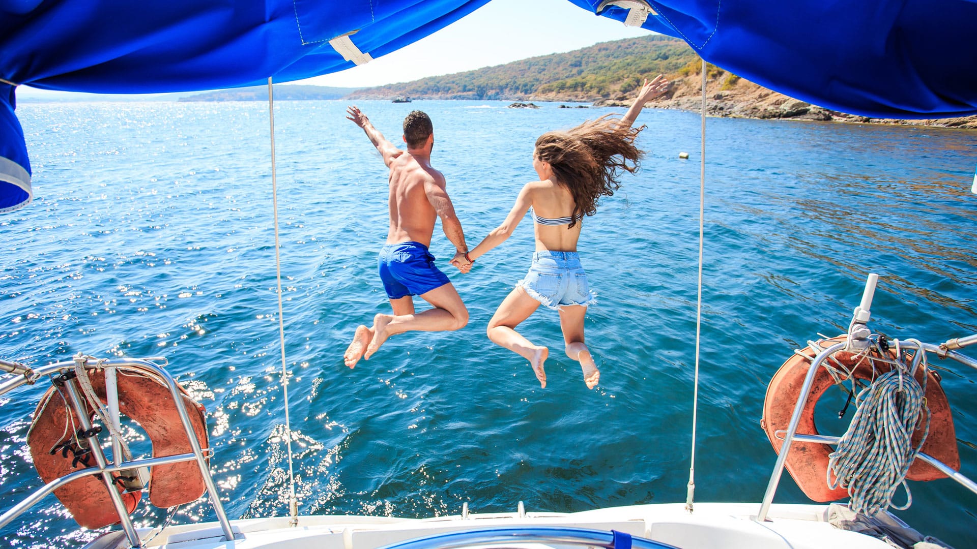 couple jumping off sailboat