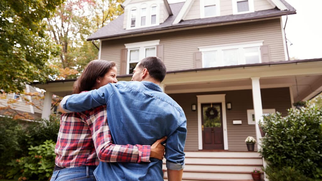 happy homeowners in front of house