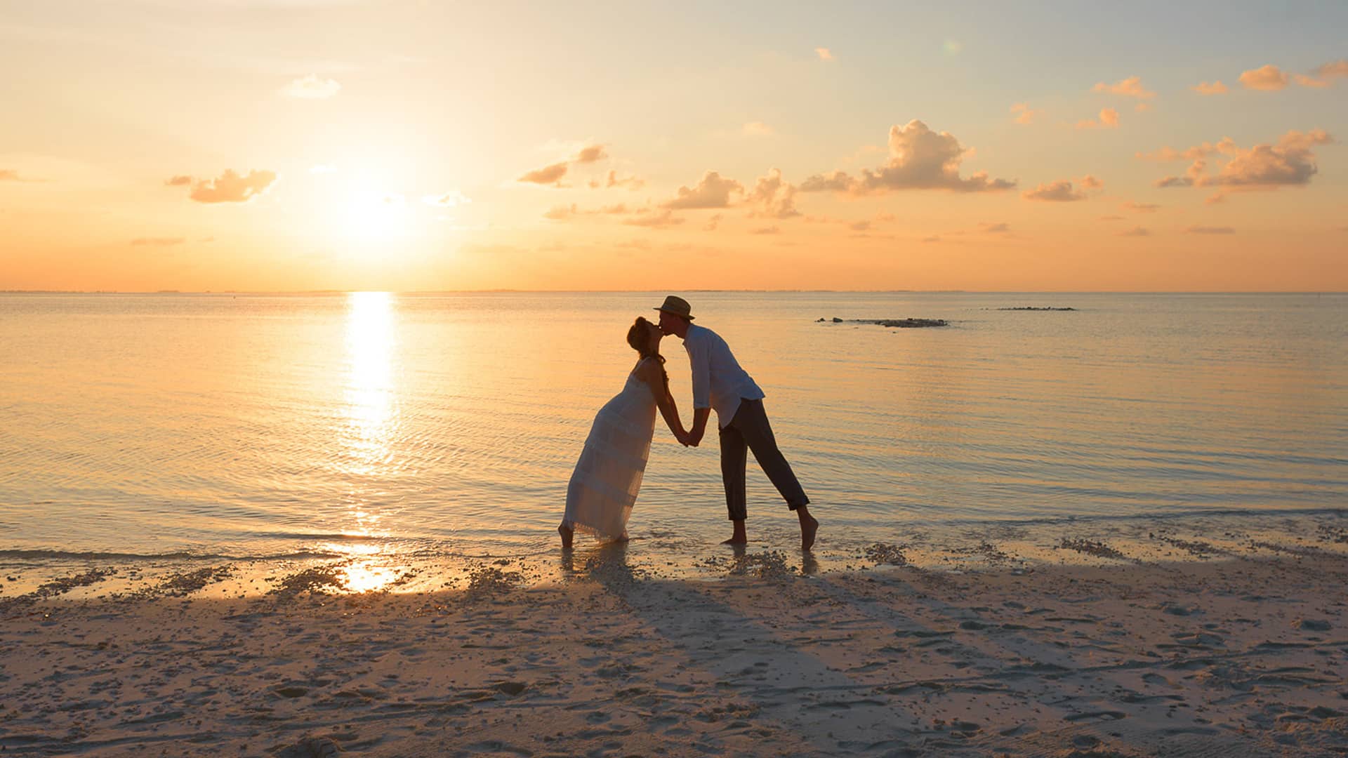 Couple kissing on beach during honeymoon