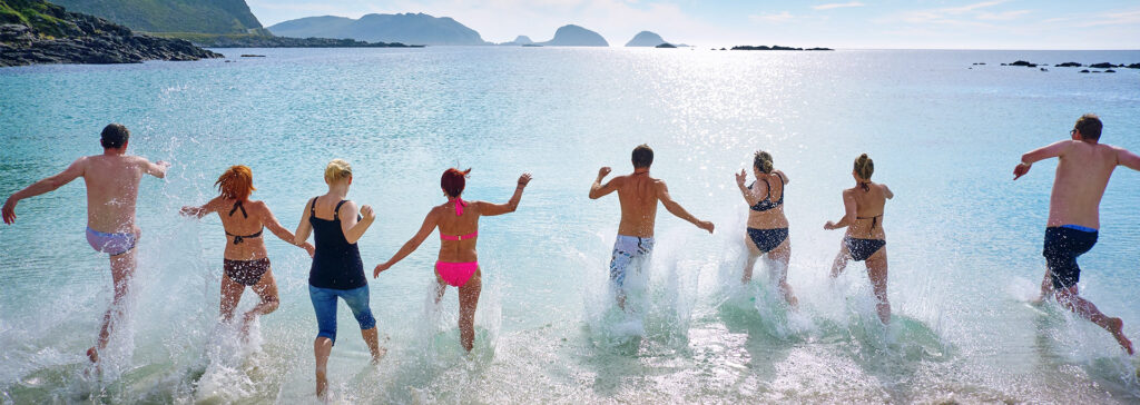 group of friends running into ocean