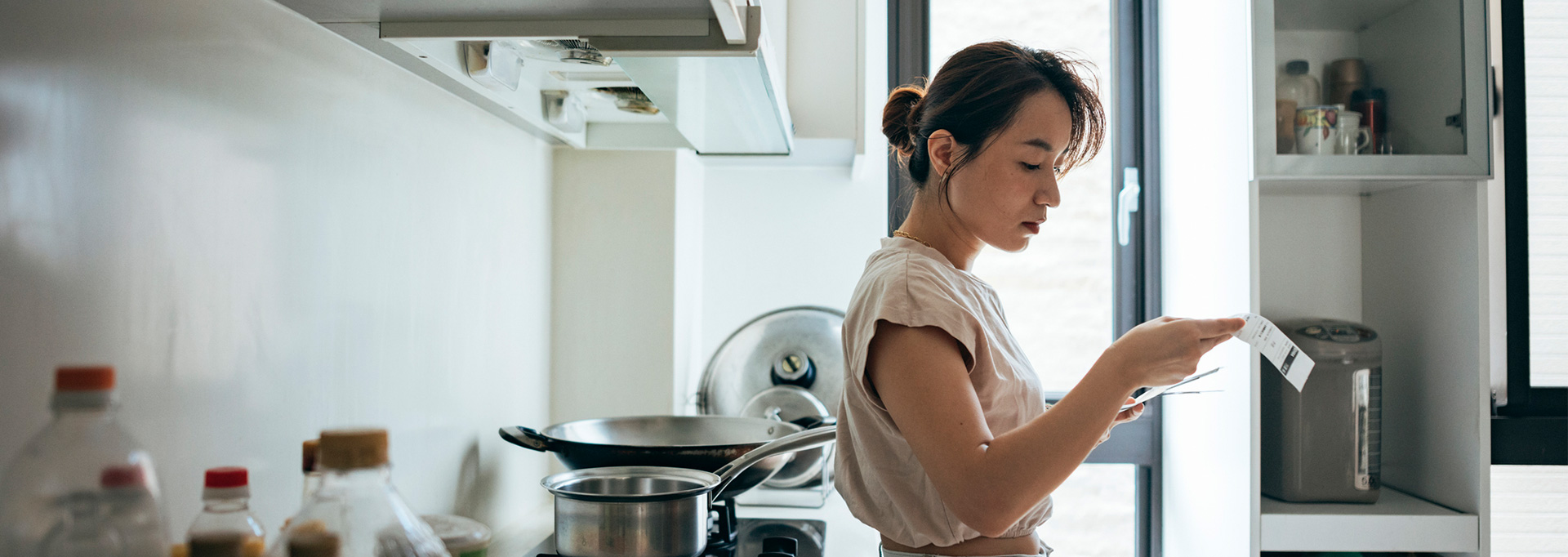 woman in kitchen looking at receipts